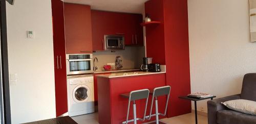 a small kitchen with red cabinets and a washing machine at Hikoa Hendaia-Hendaye plage in Hendaye