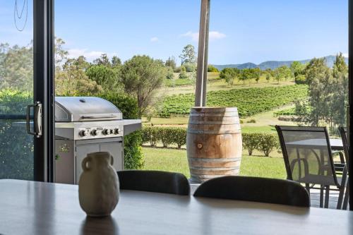 a table with a stove and a view of a vineyard at Travertine Vineyard Retreat - Stay Among the Vines in Pokolbin