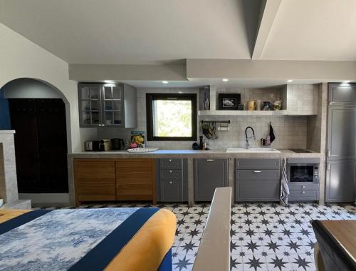 - une cuisine avec des placards gris et un lit dans une chambre dans l'établissement Maisonnette climatisée, à Aix-en-Provence