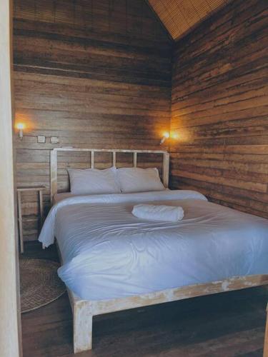 Ce lit se trouve dans un dortoir doté de murs en bois. dans l'établissement Purnama Home, à Toyapakeh