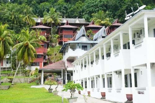 a large white building with palm trees in the background at Analisa Beach Resort in Pangkor