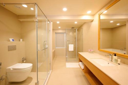 une salle de bain avec une douche, des toilettes et un lavabo dans l'établissement ABN Sarovar Portico Jim Corbett Dhikuli, à Rāmnagar