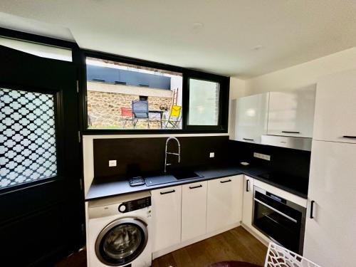 a kitchen with a washing machine and a window at Charmant studio 37m2 Jardin privatif in Malakoff