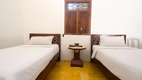 two beds in a room with a table between them at The Mangkoro Hotel by Sinergi in Yogyakarta