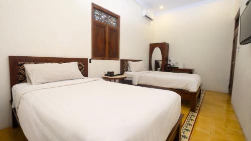 a hotel room with two beds and a window at The Mangkoro Hotel by Sinergi in Yogyakarta