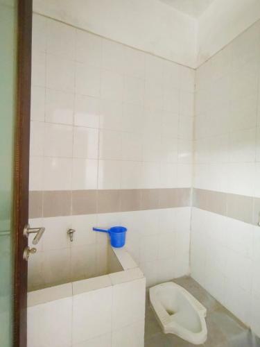 a bathroom with a toilet in a white tiled room at Cheery Home Surabaya 10 mins toll near Pakuwon Mall in Surabaya