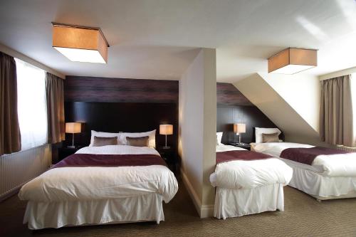 a hotel room with two beds and two windows at The King's Highway Wetherspoon in Inverness