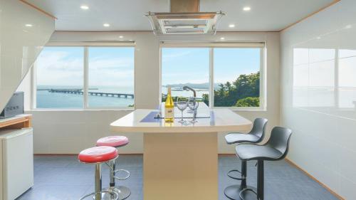 Una cocina con una encimera con dos taburetes y ventanas. en Samcheok Peacehousing Spa Pet Pension, en Samcheok