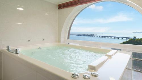 a bathroom with a bath tub with an arch window at Samcheok Peacehousing Spa Pet Pension in Samcheok
