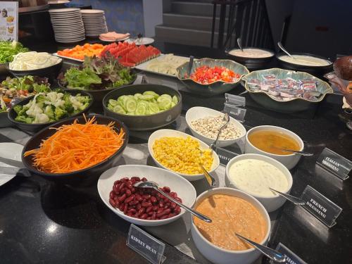 a buffet filled with bowls of different types of food at The Yama Hotel Phuket in Kata Beach