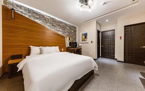 a bedroom with a large white bed and a brick wall at Rings Hotel in Gunsan