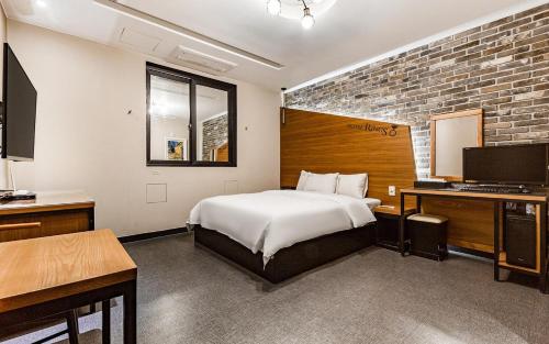 a bedroom with a bed and a desk and a television at Rings Hotel in Gunsan