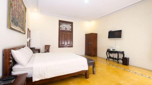 a bedroom with a bed and a desk and a television at The Mangkoro Hotel by Sinergi in Yogyakarta