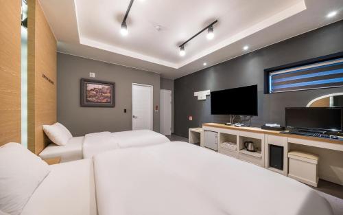 a bedroom with two beds and a flat screen tv at Rings Hotel in Gunsan