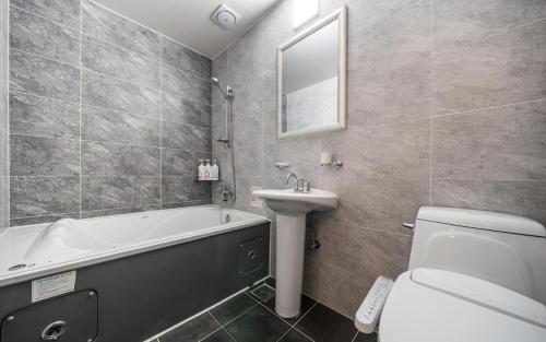 a bathroom with a tub and a sink and a toilet at Rings Hotel in Gunsan