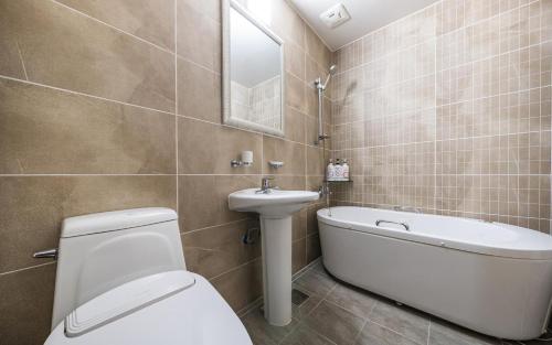 a bathroom with a toilet and a sink and a bath tub at Rings Hotel in Gunsan