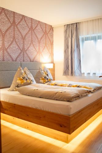 a bedroom with a large bed with a wooden frame at Almtalhotel Appartements in Pettenbach in Pettenbach