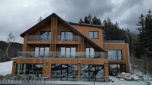 a house with glass windows and a roof at The Pines Bucegi Lodge in Bran