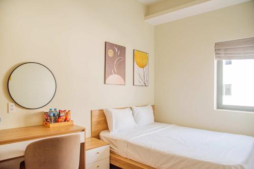a bedroom with a bed and a desk and a mirror at The Vista Châu Đốc Hotel in Chau Doc