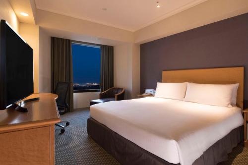 a hotel room with a large bed and a television at Hilton Tokyo Narita Airport in Narita