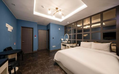 a bedroom with a large white bed and blue walls at Rings Hotel in Gunsan