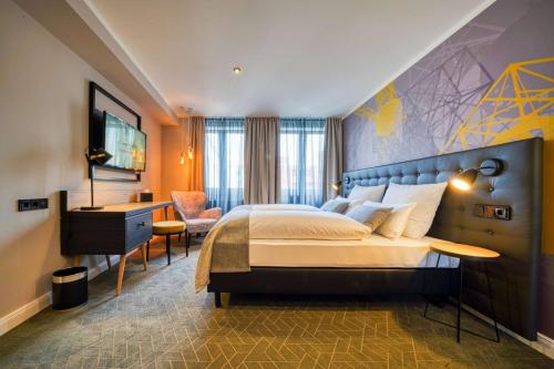 a hotel room with a large bed and a desk at Vienna House Easy by Wyndham Dortmund City in Dortmund