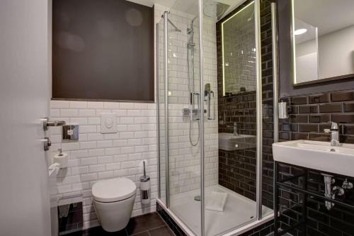 a bathroom with a shower and a toilet and a sink at Vienna House Easy by Wyndham Dortmund City in Dortmund