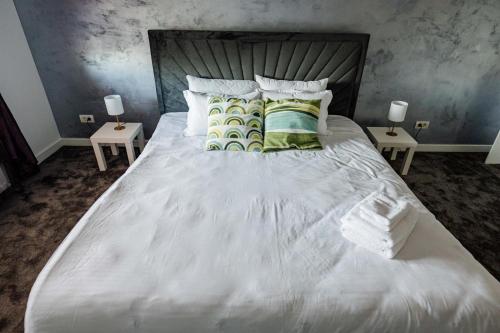 a bedroom with a white bed with two tables at Casa Korman in Giarmata