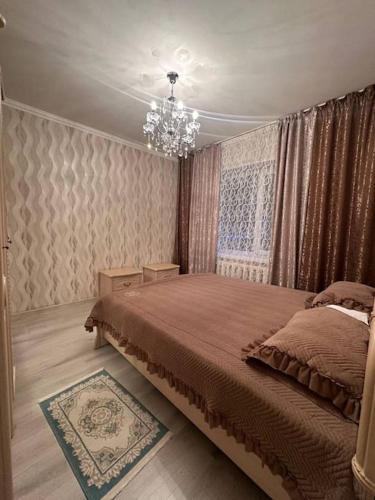a bedroom with a large bed and a chandelier at 3х комнатная по Толе би in Taraz