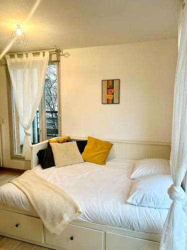 une chambre avec un lit blanc avec des oreillers jaunes dans l'établissement Studio Berlioz - charme, confort, terrasse privée, à Villeurbanne
