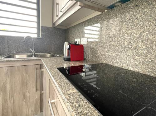 a kitchen with a red appliance on a counter at Baywatch - Pieds dans l'eau avec piscine in Baie du Tombeau