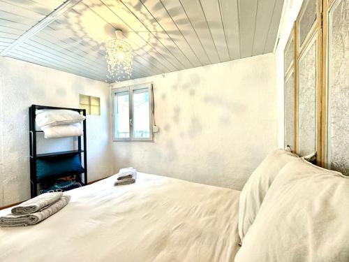 une chambre avec un grand lit blanc et une fenêtre dans l'établissement Maison Entre Pont et Cathédrale, à Béziers