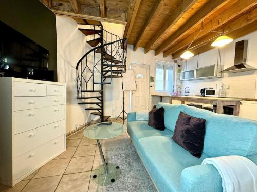 - un salon avec un canapé bleu et un escalier en colimaçon dans l'établissement Maison Entre Pont et Cathédrale, à Béziers