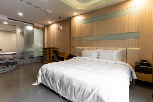 a bedroom with a large white bed and a bathroom at OHYA Chain Boutique Motel-Xinying in Xinying