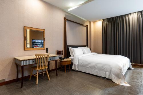 a hotel room with a bed and a desk and a bed and a mirror at OHYA Chain Boutique Motel-Xinying in Xinying
