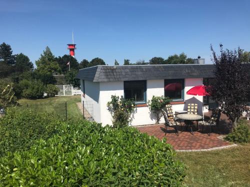 a small white cottage with a table and chairs in a yard at Ferienhaus Jordsand in Schausende