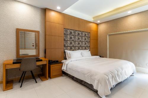 a bedroom with a bed and a desk and a mirror at OHYA Chain Boutique Motel-Xinying in Xinying