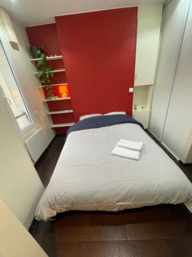 Cette petite chambre comprend un lit avec un mur rouge. dans l'établissement Cocon chaleureux & charmant - Nation, à Paris