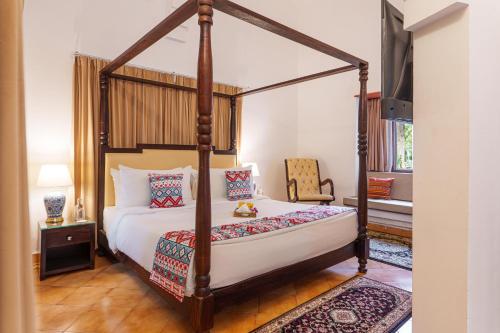 a bedroom with a four poster bed and a chair at amã Stays & Trails Lotus Dhauj , Haryana in Faridabad