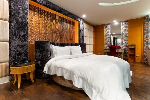 a bedroom with a large white bed and a wall at OHYA Chain Boutique Motel-Xinying in Xinying