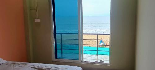 a bedroom with a window looking out at the beach at Aisiri comforts beach stay and cafe in Gokarn