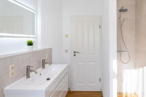 a white bathroom with two sinks and a shower at Ferienhaus Waldheide in Zempin