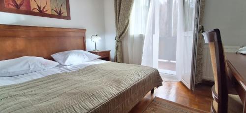 a bedroom with a bed with a wooden headboard and a window at Pensjonat Witoldówka in Krynica Zdrój
