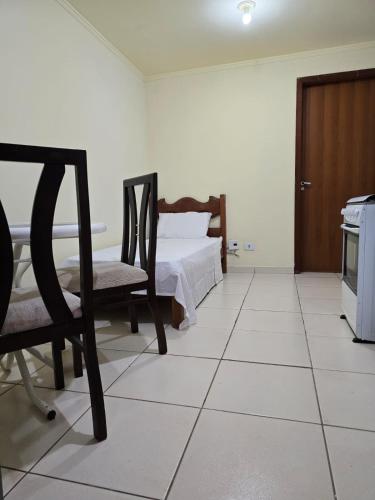 a bedroom with a bed and two chairs in it at Edificio Hayannes - 1 Quarto - 1 Cozinha - 1 Banheiro - Garagem Coberta - Self Check in -Taxa Para Hospede Com Pets in Maringá