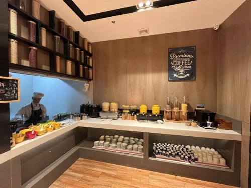 a man standing behind a counter in a coffee shop at Echarm Hotel Kunming Baita Road Huidu International Store in Kunming