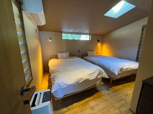 two beds in a small room with a window at ルネ熱海伊豆山villa134 in Atami