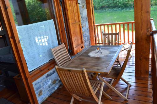une table et des chaises en bois sur un porche dans l'établissement Apartamento con piscina en Osseja, à Osséja