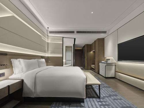 a bedroom with a large bed and a flat screen tv at Hilton Shanghai Hongqiao International Airport in Shanghai