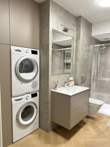 a bathroom with a washing machine and a sink at Apartament Premium Zamkowa A14 in Tczew