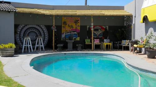 a swimming pool in front of a house with a patio at Kombi Cove Bloubergstrand in Cape Town